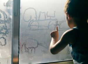 Boy Drawing in Window Condensation